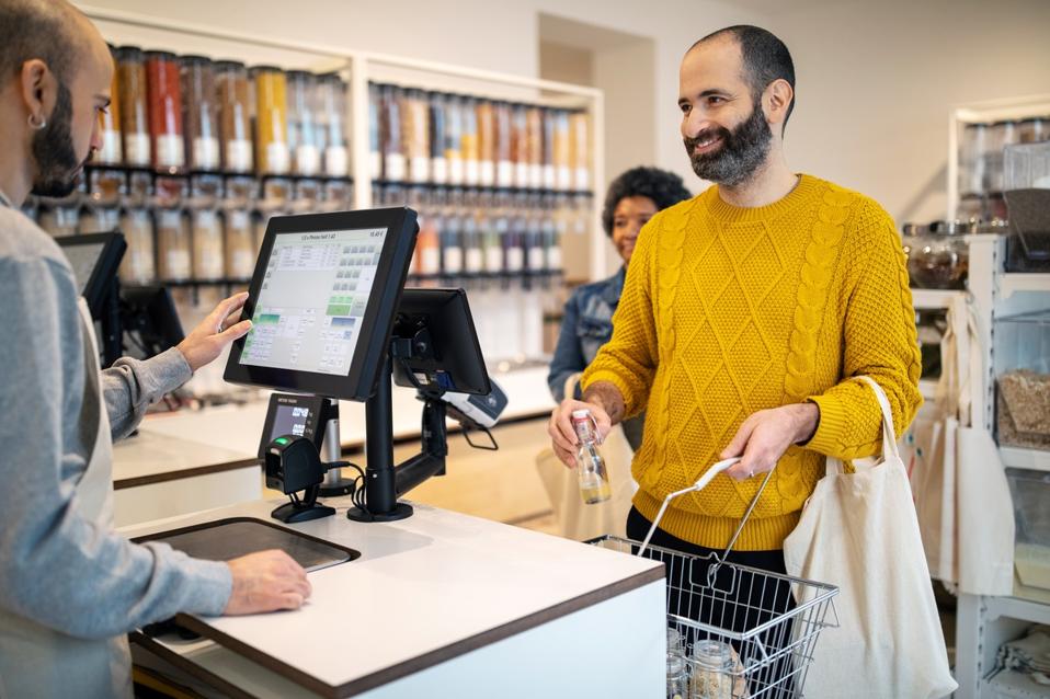 Smiling bearded man buying products from owner at zero waste store