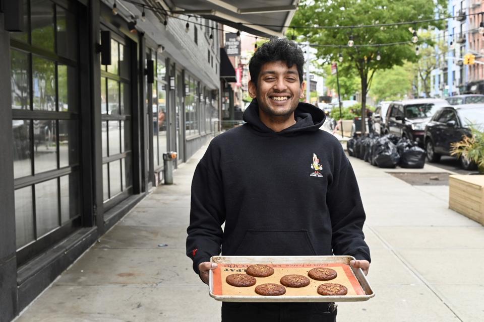 Mohit Sahoo with a sheet pan full of cookies outside of Sobre Masa