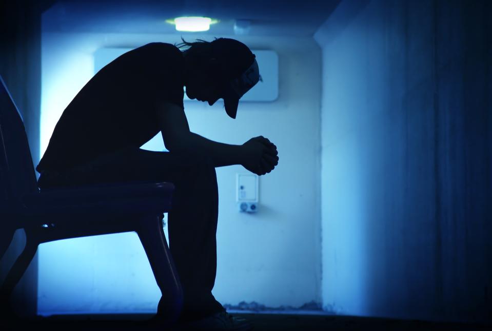 young depressed man sitting bent over on chair
