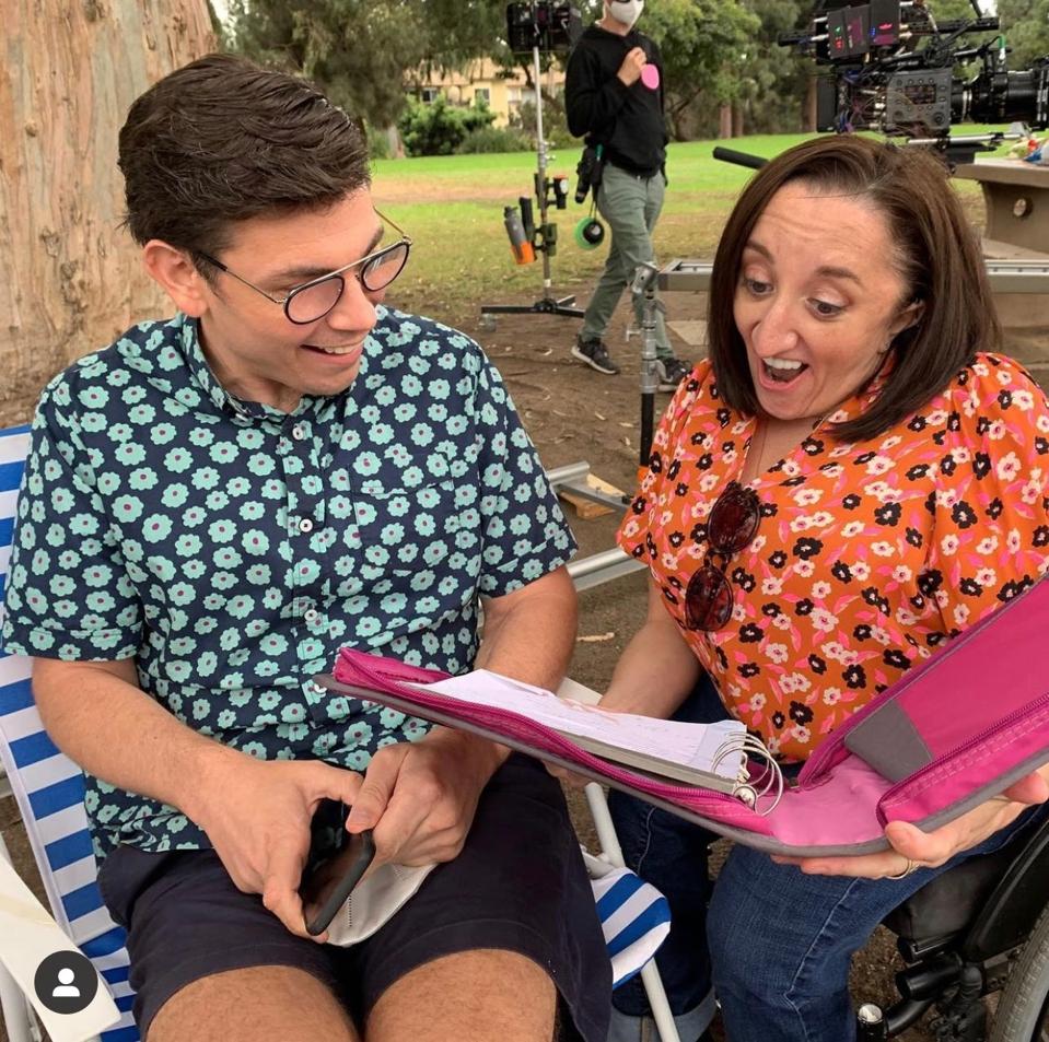 A white man with glasses looks at a pink binder with a white woman.