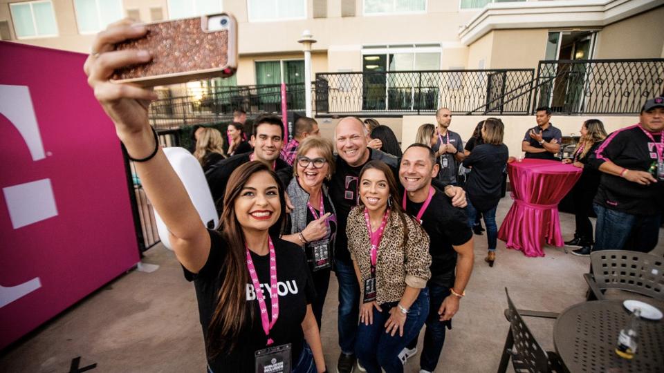 Six coworkers taking a selfie at a T-Mobile event.