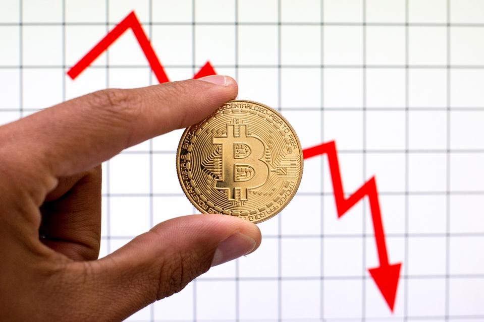 In this photo illustration, a Bitcoin is seen with graph in...