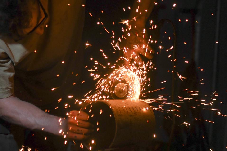 An artist welder at work with an angle grinder.