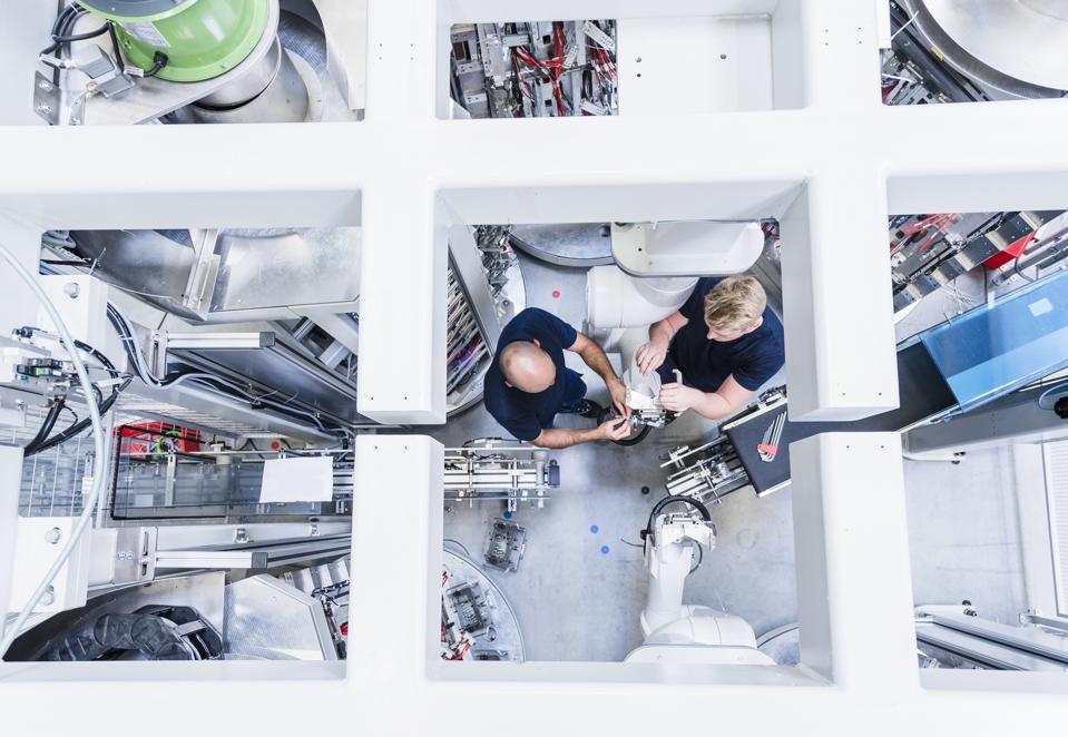 Top view of two colleagues working at industrial robot in modern factory