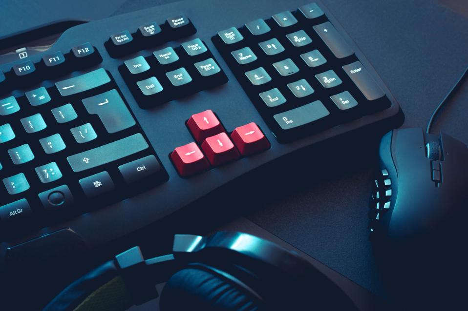 A picture of a gaming keyboard, headphones and mouse on black table