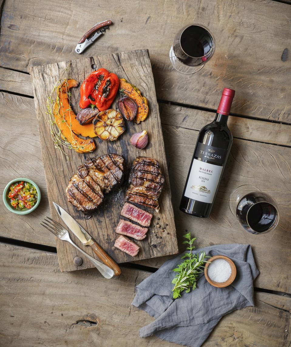 Terrazas de los Andes Malbec on table with glasses and grilled steak and fixings