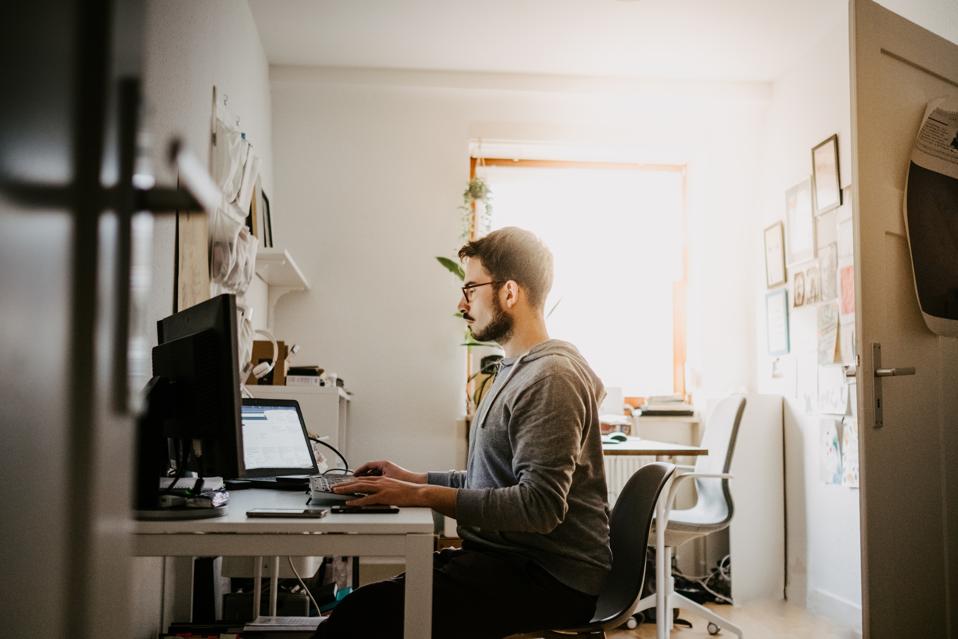 Young businessman using computer while sitting at desk in home office