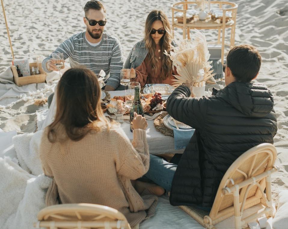 Four people sitting on beach chairs enjoying a picnic 