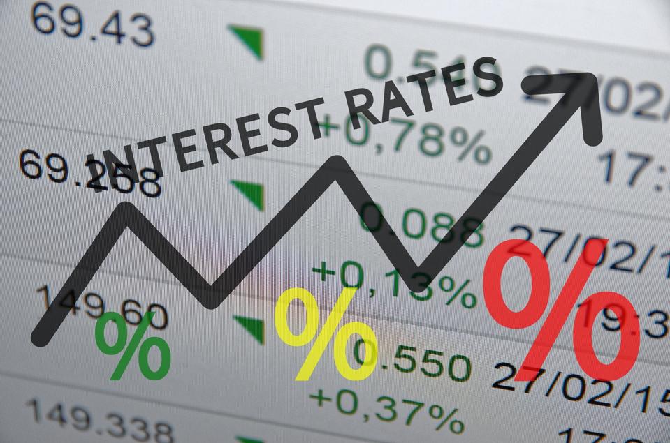 Words ″interest rates″ over upward arrow, with finance data in background
