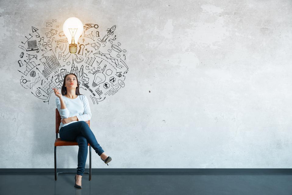 Thoughtful young woman sitting in interior surrounded by creative business sketch and lightbulb. Leadership concept