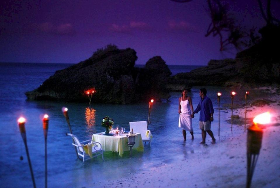 Lovers walk along the water's edge at Cambridge Beaches Resort and Spa, Bermuda.