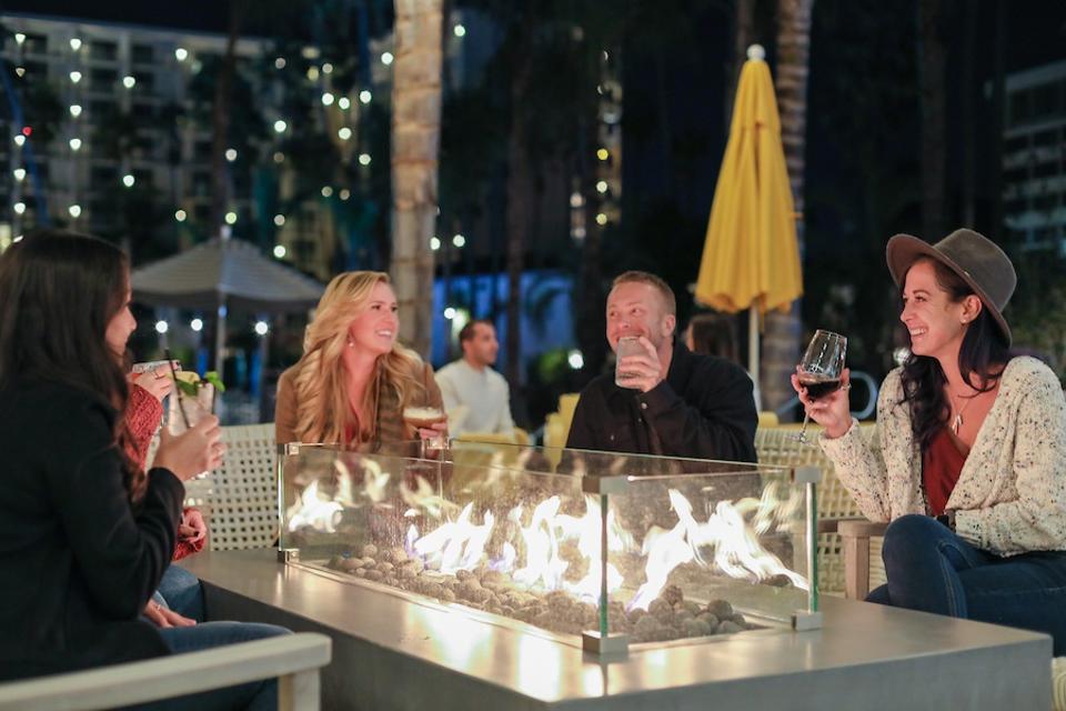 People toasting in front of a modern firepit