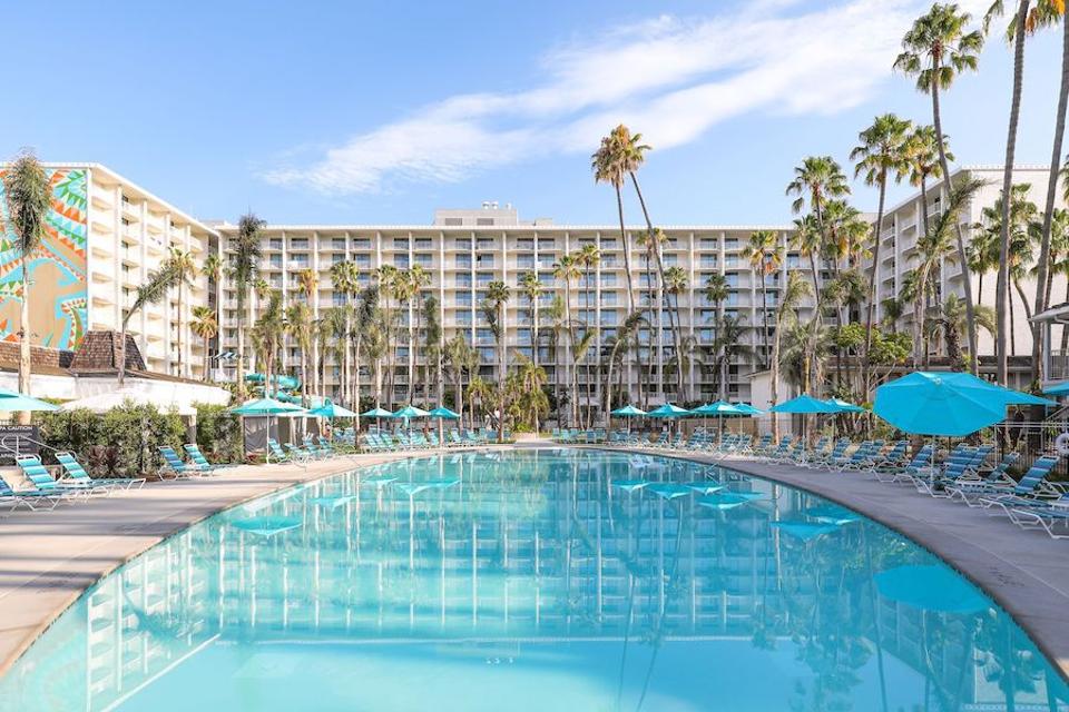 A pool and mid century modern hotel. There's a mural to the left.