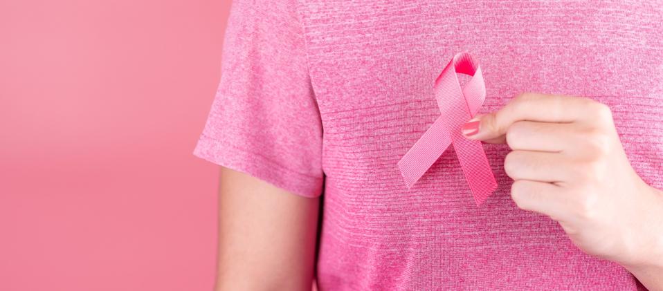 Close-Up Of Girl Holding Pink Flower Over Pink Background