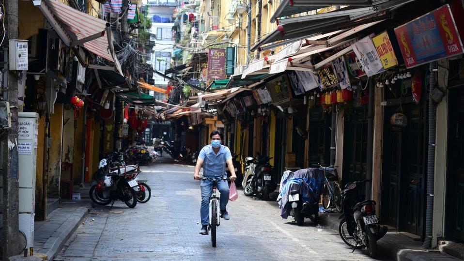 Man rides bicycle down street in Hanoi, Vietnam