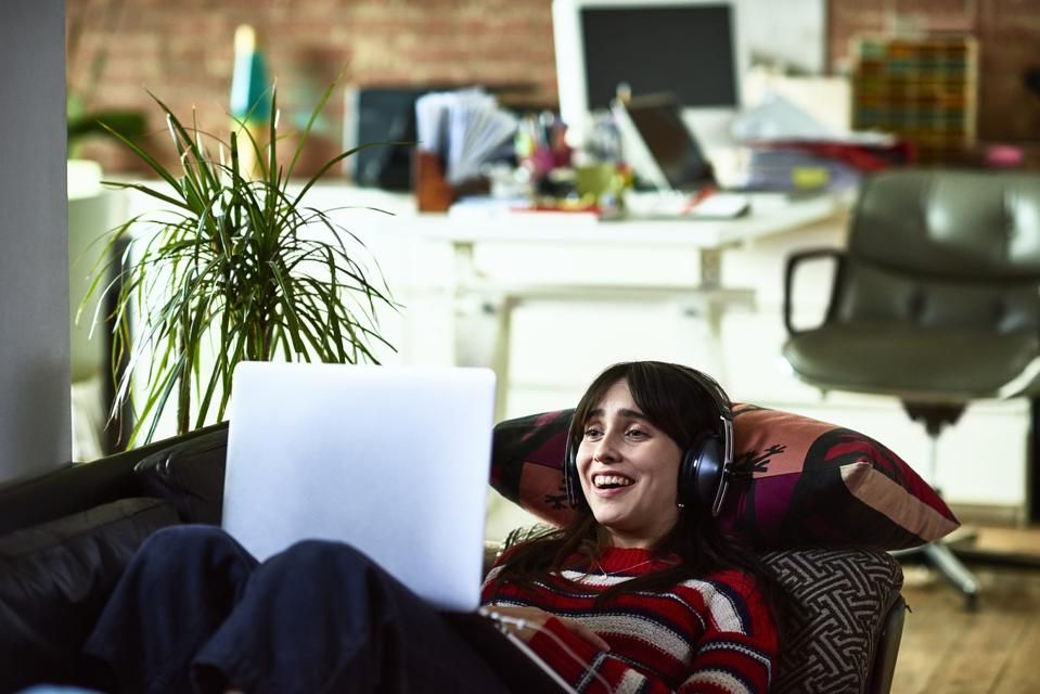 Cheerful young woman watching movie and laughing