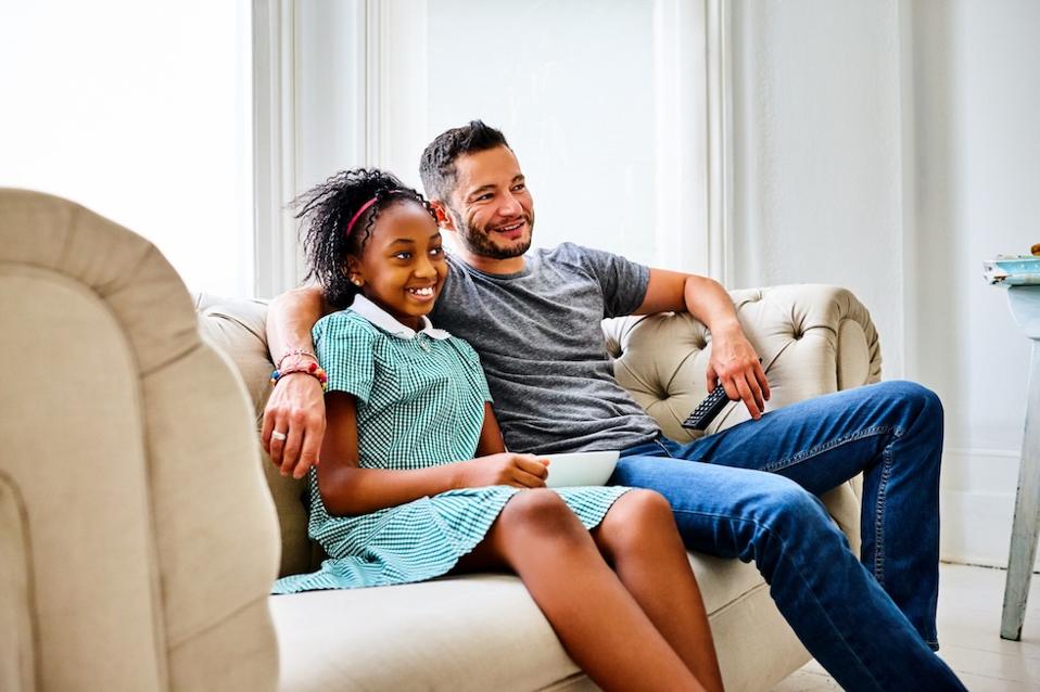 A trans man and his daughter watch TV