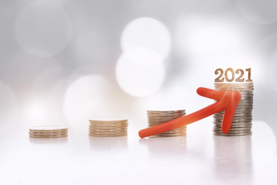 Number 2021 and stack of coins with red arrow upwards on abstract background