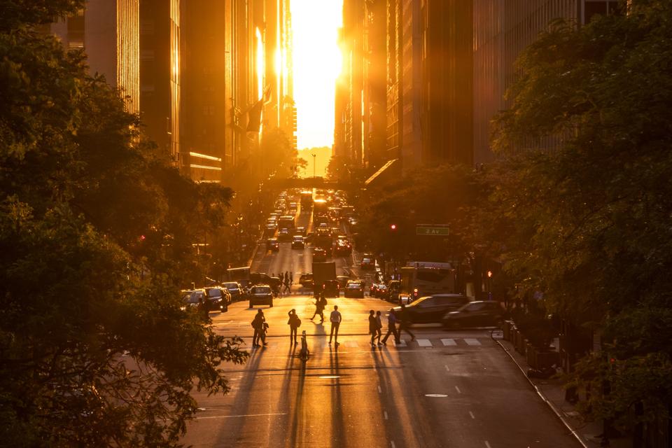 Rays of sunlight shining down on the people and traffic at the intersections along 42nd Street in New York City
