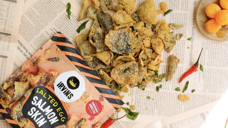 An open bag of Irvins' Salted Egg Salmon Skins on newspaper.