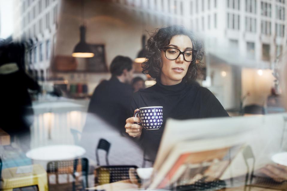Female business professional reading a newspaper in cafe