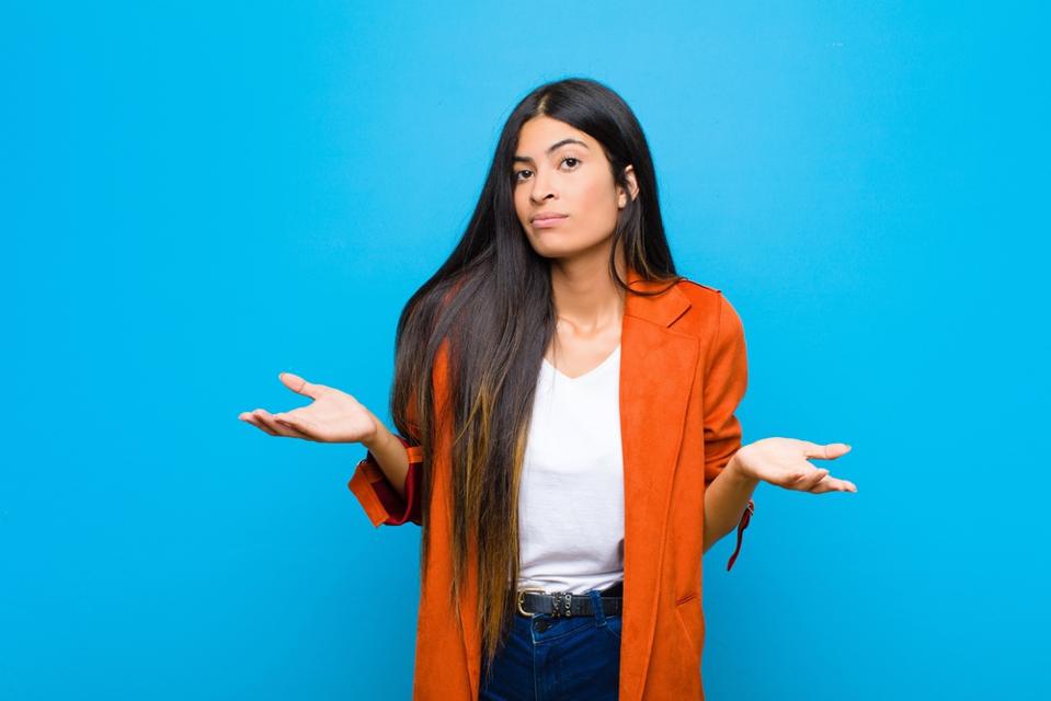 Young Latina businesswoman shrugs her shoulders with exasperation