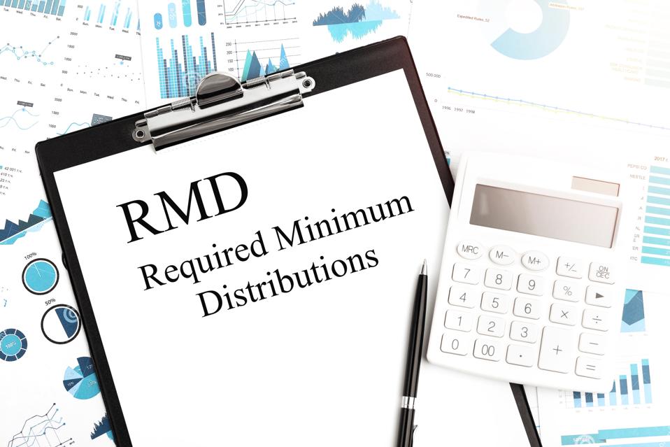 Required Minimum Distributions written on clipboard on top of calculator, pen and charts.