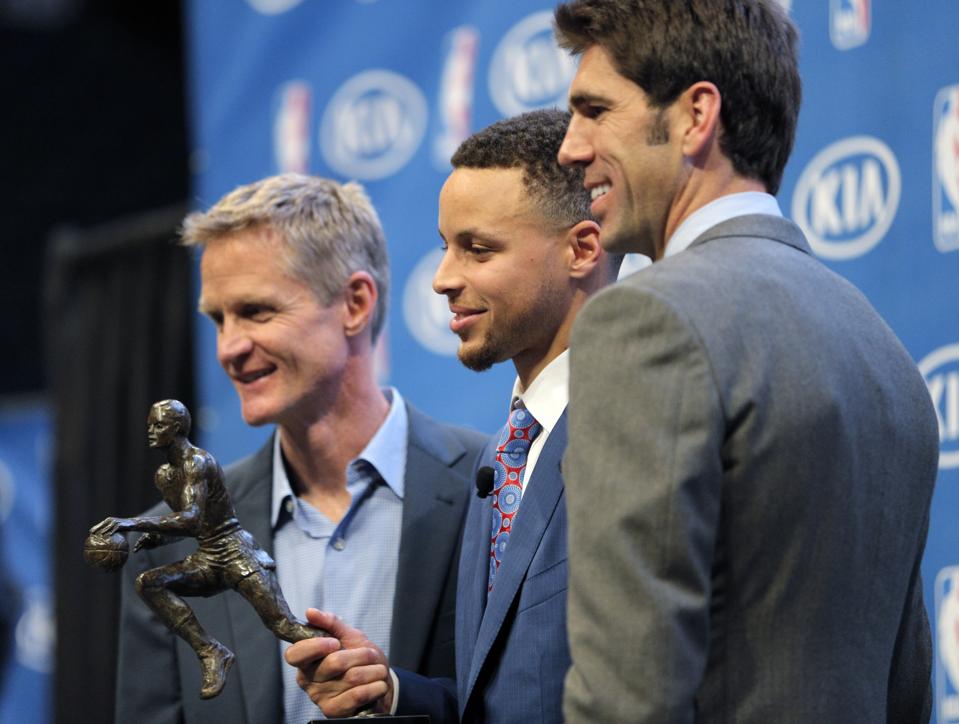 Stephen Curry poses with coach Steve Kerr, left, and General Manager Bob Myers, right, and his 2016 trophy during a ceremony where he was awarded the 2016 Kia NBA Most Valuable Player award.