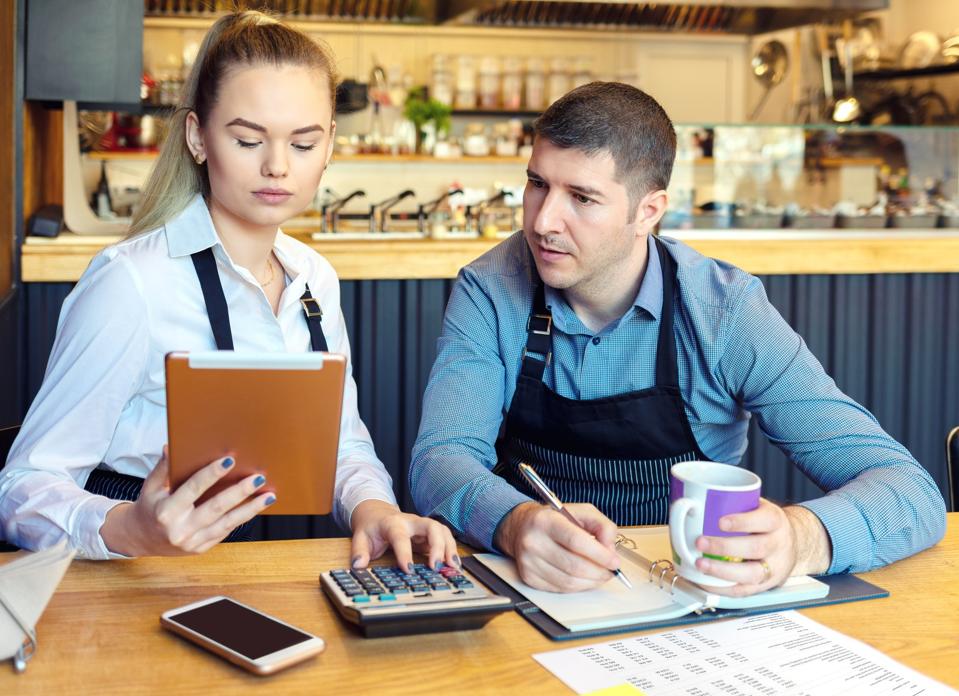 Small business owners calculating their monthly cashflow.