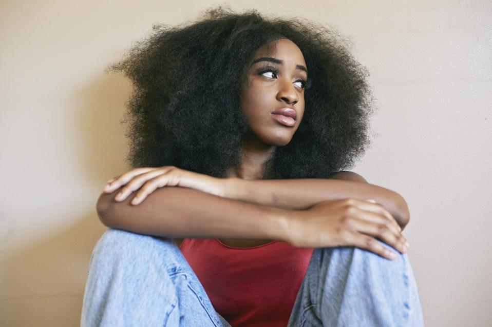 Mixed race woman sitting with arms crossed