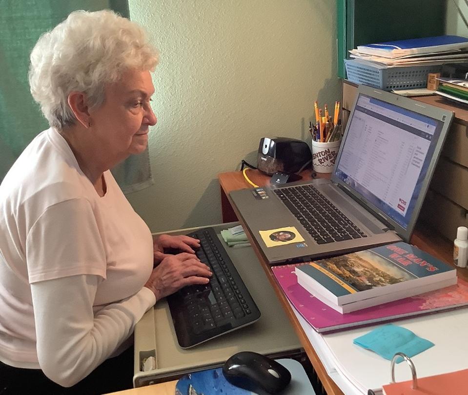 white haired mature lady typing on computer