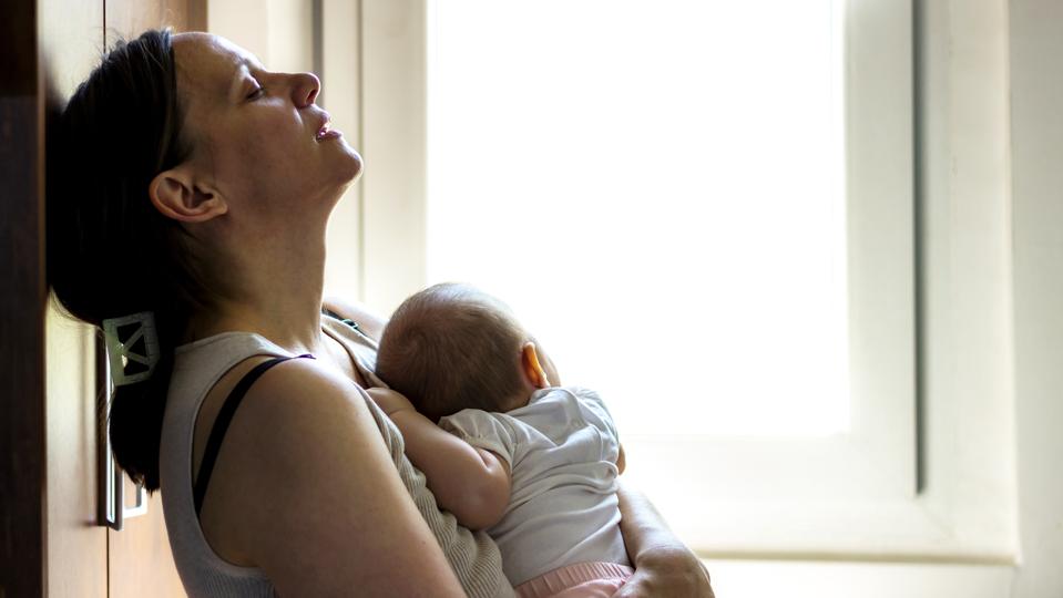 A tired mother holds her sleeping baby.