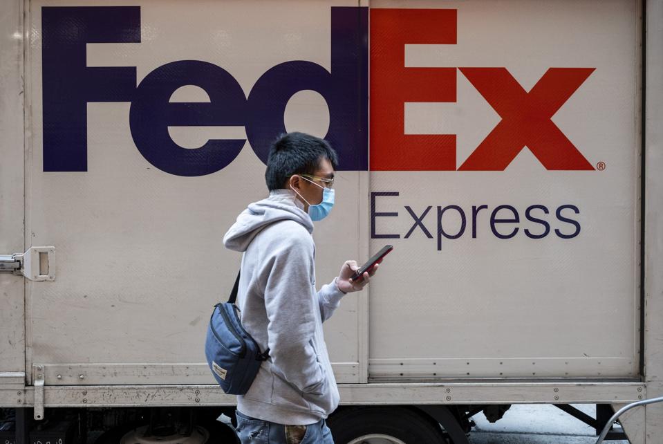 A man walks past the American FedEx Express delivery truck...