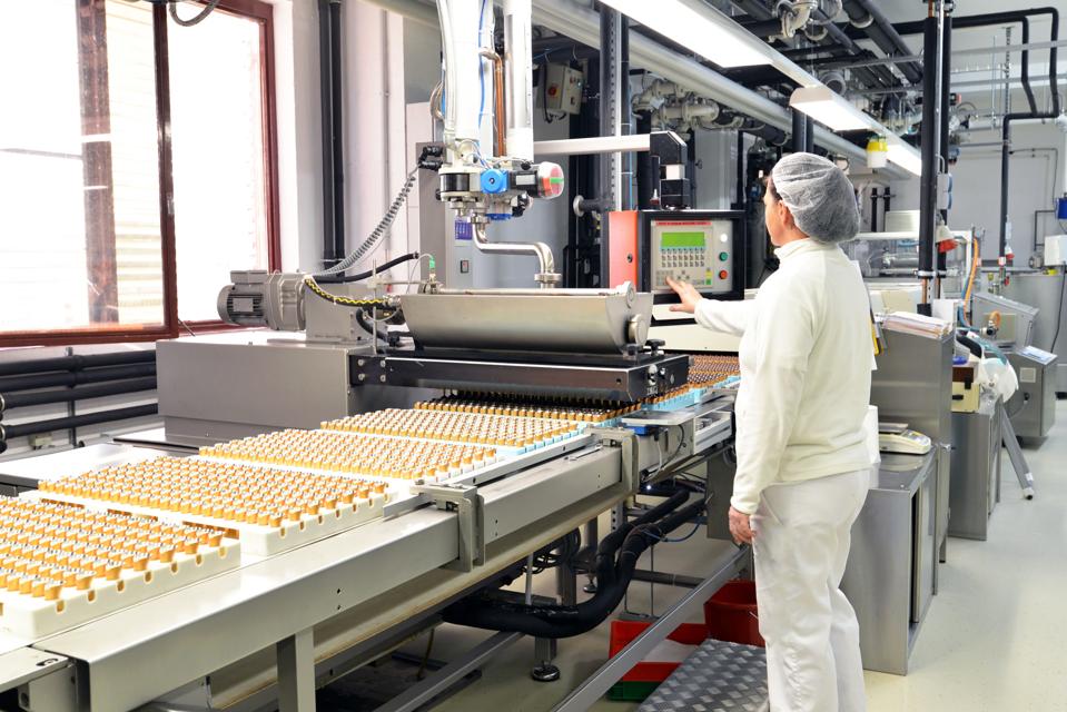 Production of pralines in a factory for the food industry - conveyor belt worker with chocolate.