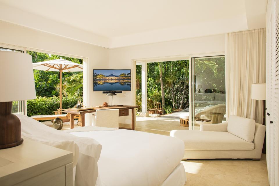 Chambre à coucher contemporaine tout en blanc avec des portes coulissantes qui mènent à l'extérieur bordé d'arbres