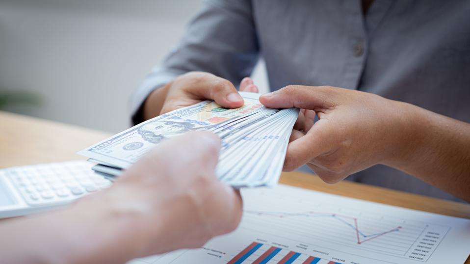 Hands of a businessman are holding large amounts of money for their employees to contribute to the company's financial success, Give money concept