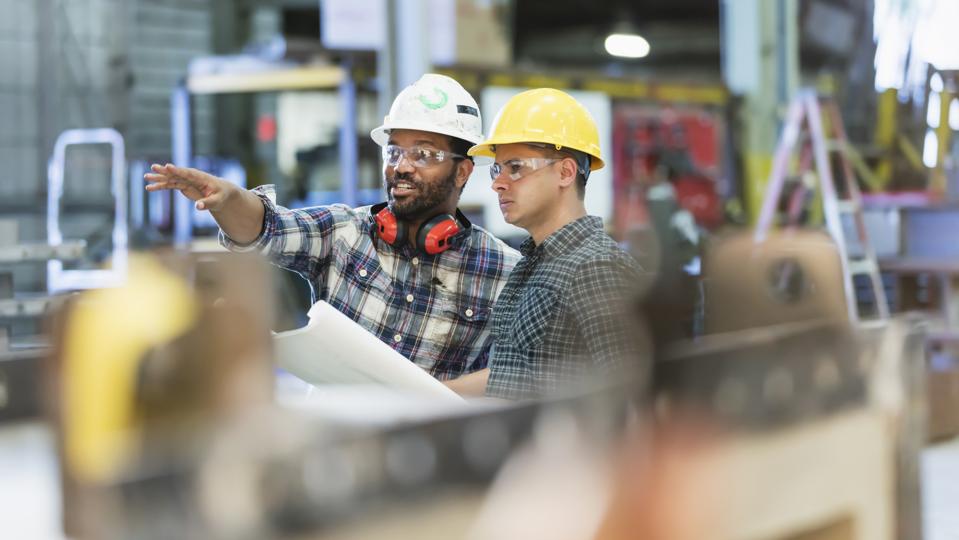 Multi-ethnic workers talking in metal fabrication plant