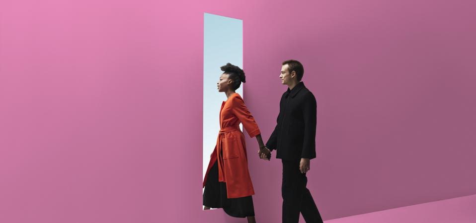 Man and woman walking through a doorway holding hands.