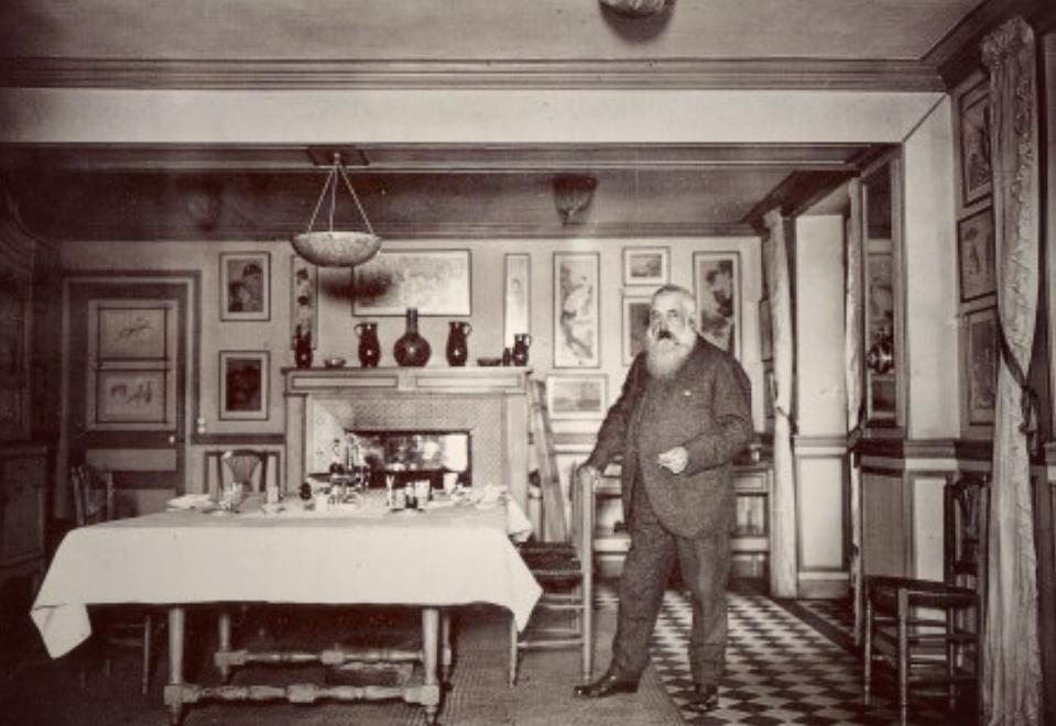 Claude Monet in the dining room at Giverny; the table is set with wine bottles and glasses
