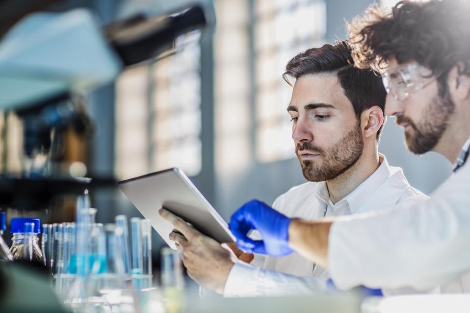 deux scientifiques utilisant une tablette numérique en laboratoire