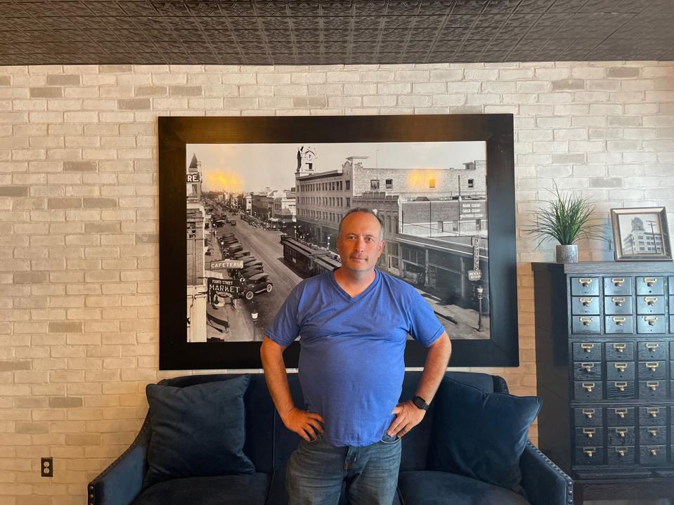 Josh Nowack in blue t-shirt with hands on hips