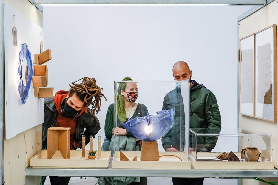 Three people looking at a display of products created from unique materials.