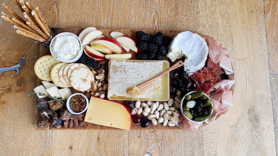 Build your cheese board from the center out and use small glasses and ramekins to hold pickles, condiments, soft cheese and breadsticks. Pictured is a variety of cheese, meats, fruits, nuts, breadsticks, cracker, condiments and dried fruit.