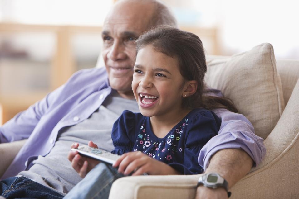 Grandfather and granddaughter watching television together