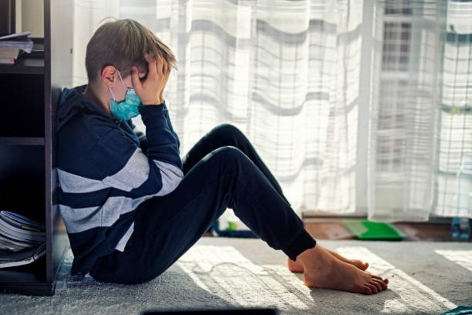 depressed boy sitting by window with face mask