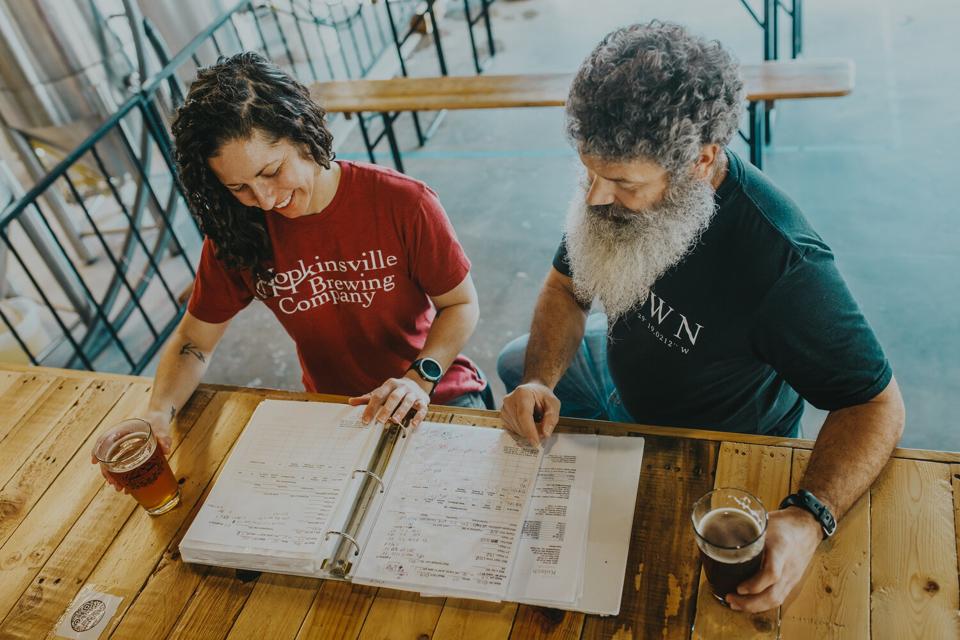 Kate Russell annd Joey Medeiros look at a menu while sipping beer.