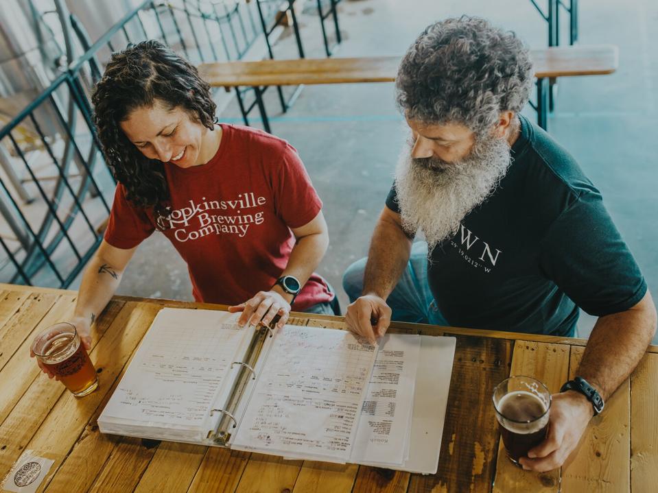 Kate Russell annd Joey Medeiros look at a menu while sipping beer.