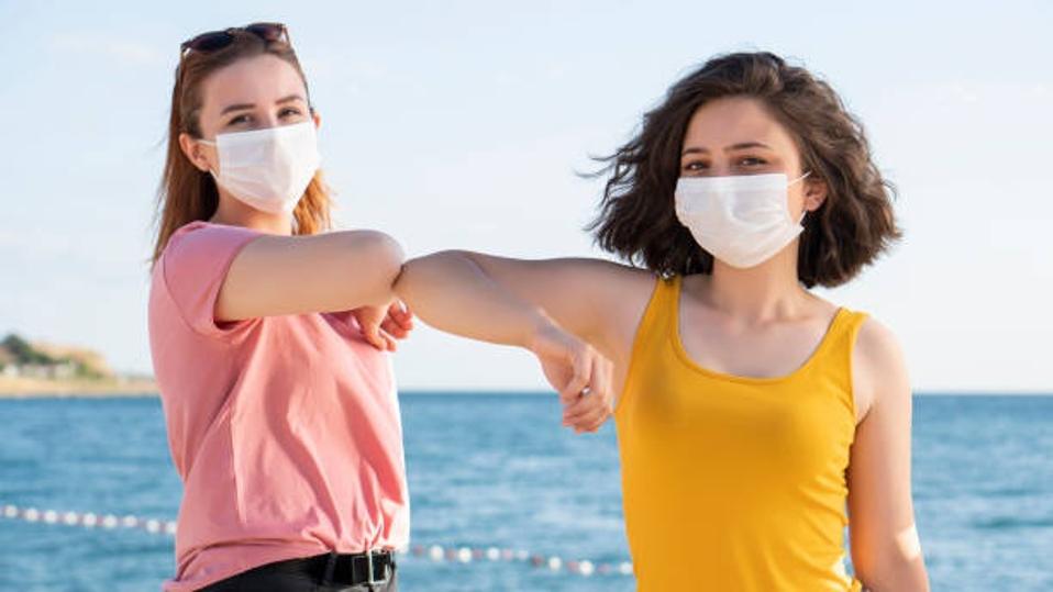 Two girls elbowing bumping with face masks