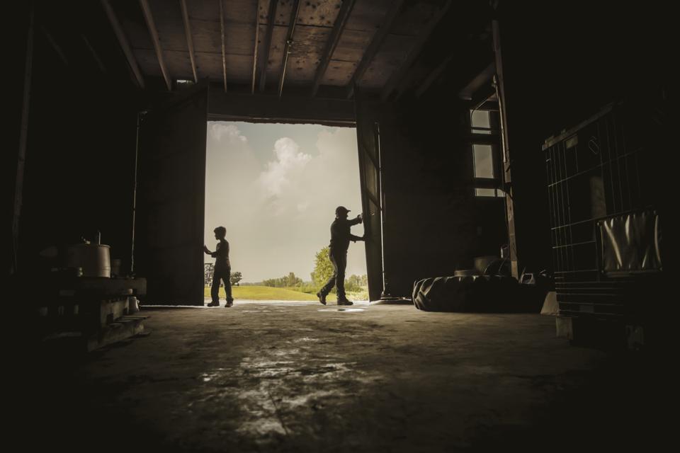 farmer and son working in barn