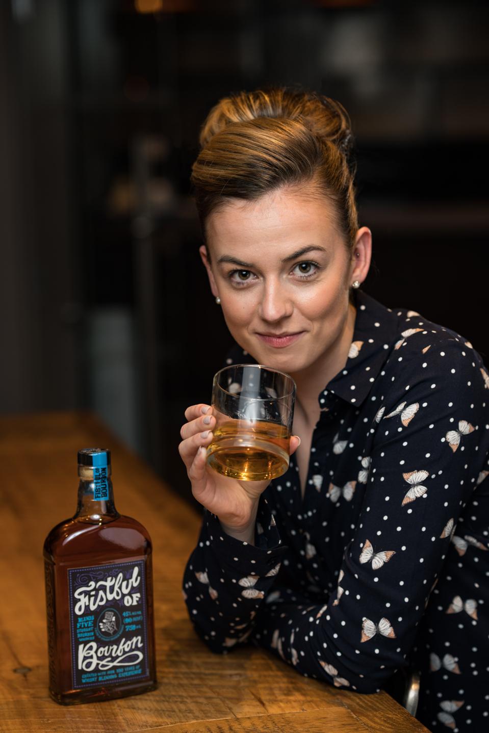 woman and a glass and bottle of bourbon